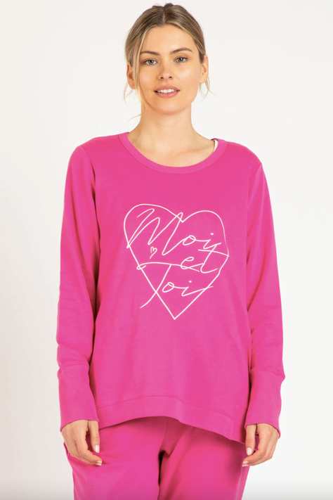 Woman wearing a pink sweatshirt with a heart design and text on a white background