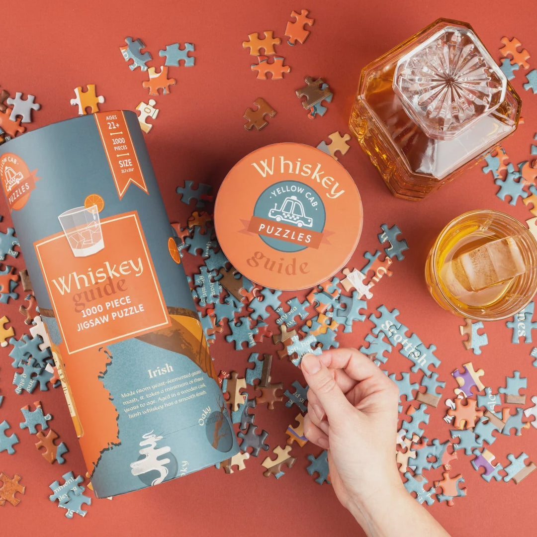 Whiskey-themed puzzle with pieces, packaging, and glasses on a red background