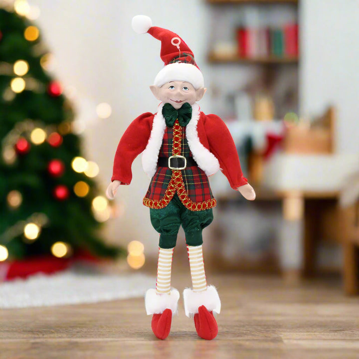 Christmas elf doll in red and green outfit with Santa hat on a white background