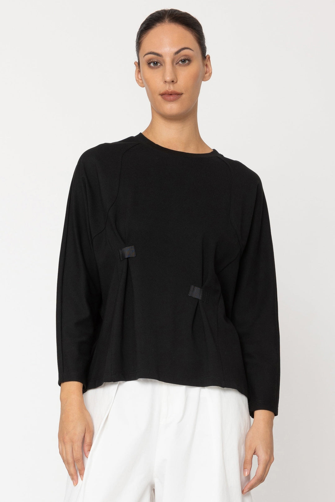 Person wearing a black top and white pants on a white background