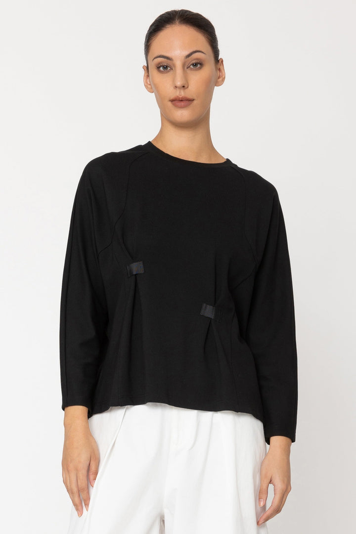 Person wearing a black top and white pants on a white background