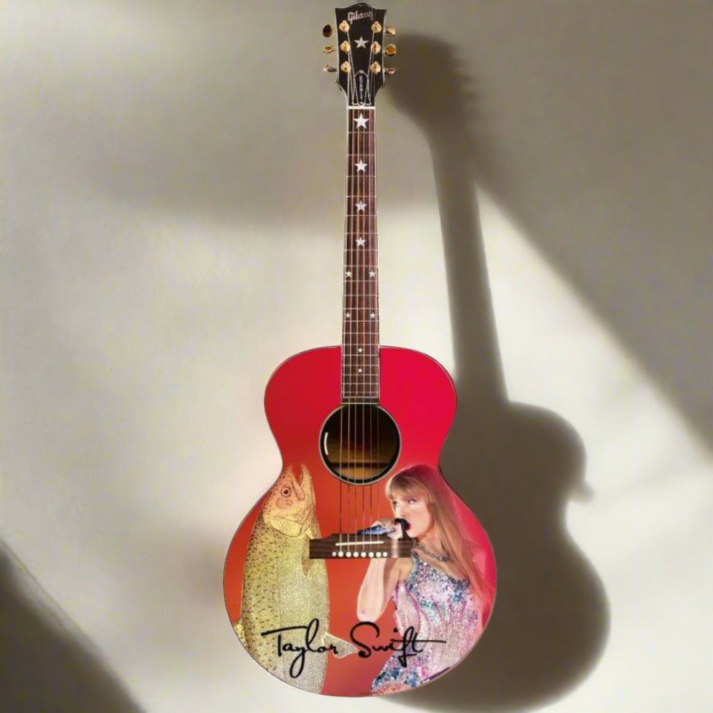 Acoustic guitar with a design of a fish and a person, featuring the name 'Taylor Swift'.