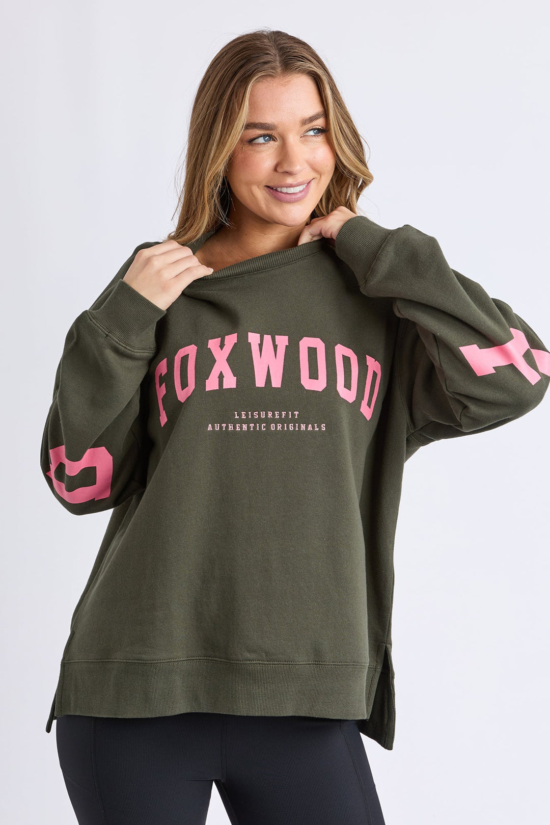 Woman wearing a green sweatshirt with 'FOXWOOD' printed in pink on a white background