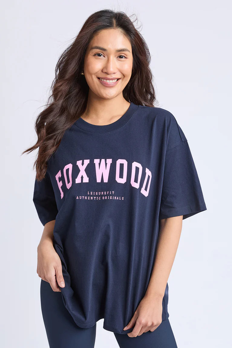 Woman wearing a navy blue t-shirt with 'FOXWOOD' printed in pink on a white background