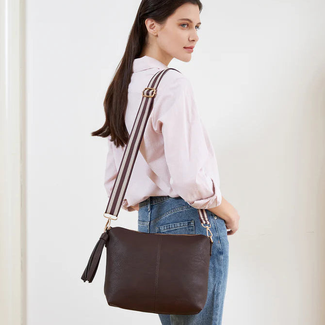 Woman carrying a brown leather handbag against a white background