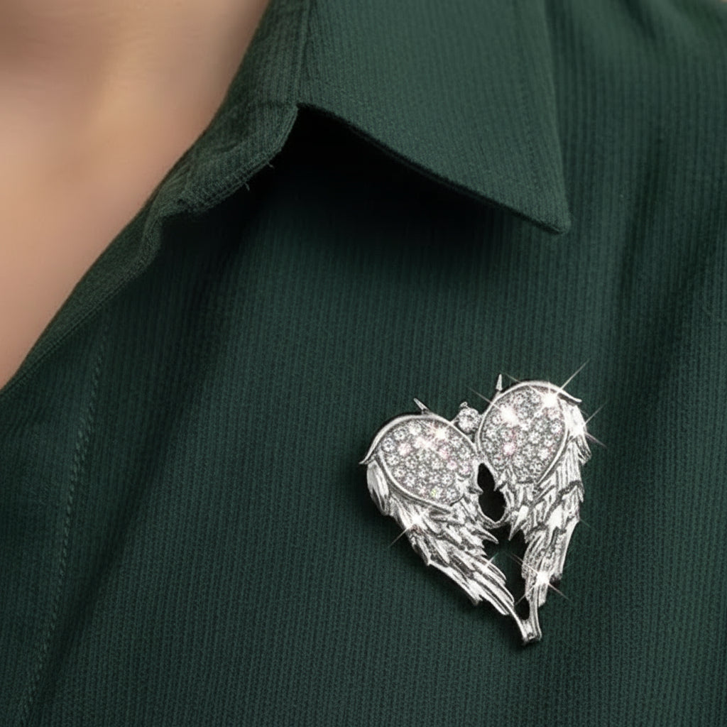 Silver angel wing brooch with gemstones on a light background with flowers