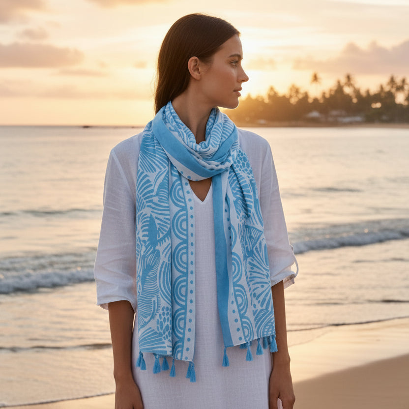 Light blue patterned scarf with tassels on a hanger against a white background