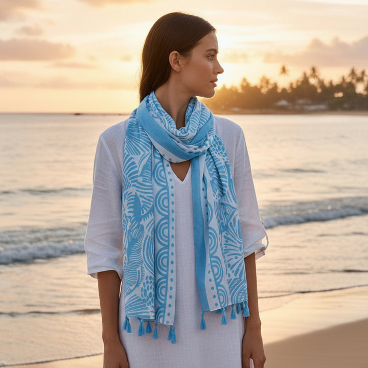Light blue patterned scarf with tassels on a hanger against a white background