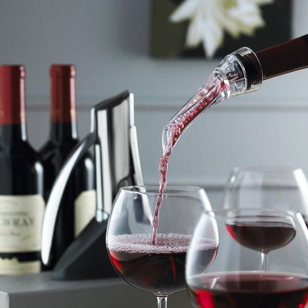Red wine being poured into a glass with bottles in the background