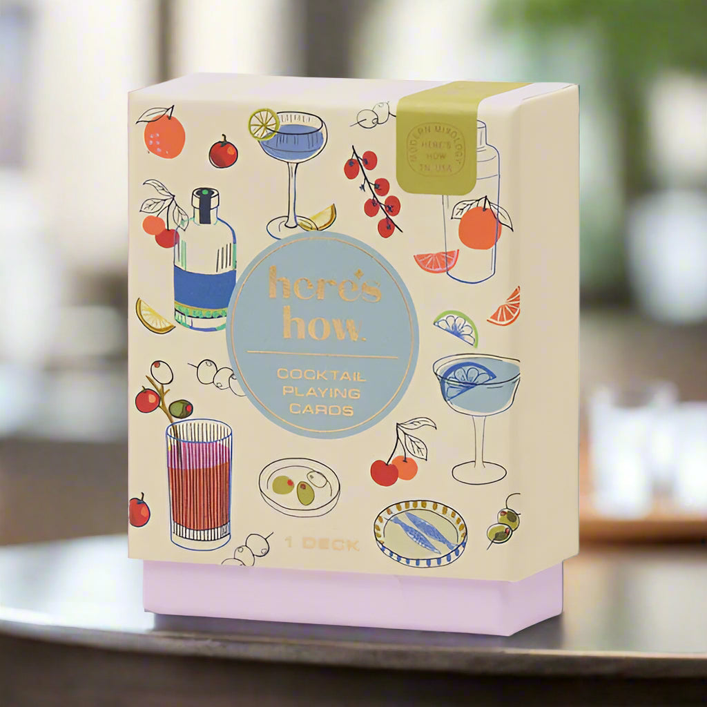 Cocktail-themed playing cards packaging with illustrations of drinks and fruits on a beige background.