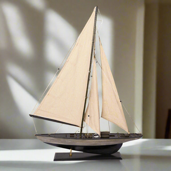 Model sailboat with beige sails on a white background