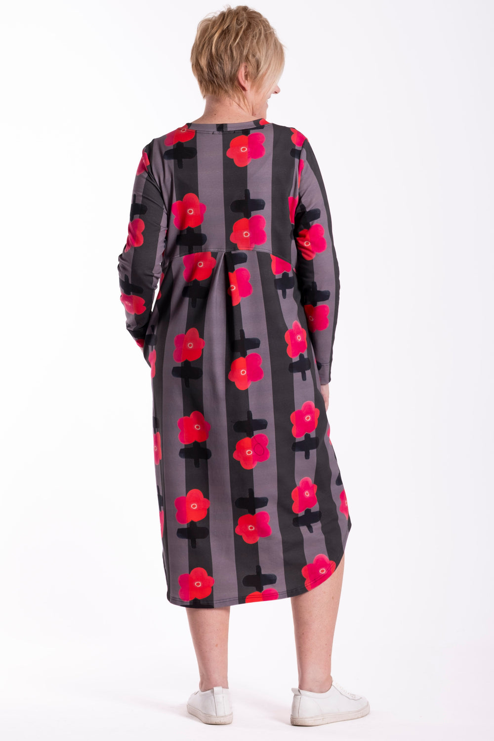 Person wearing a floral dress with red flowers on a gray background