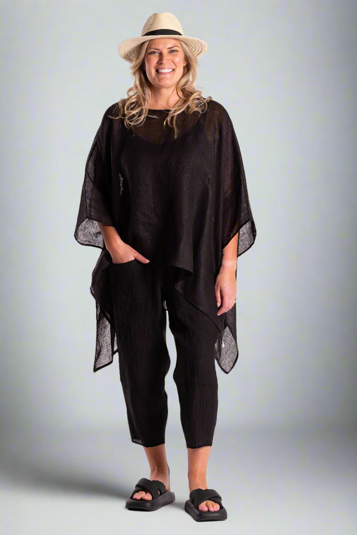 Woman wearing a black poncho and pants with a hat on a white background