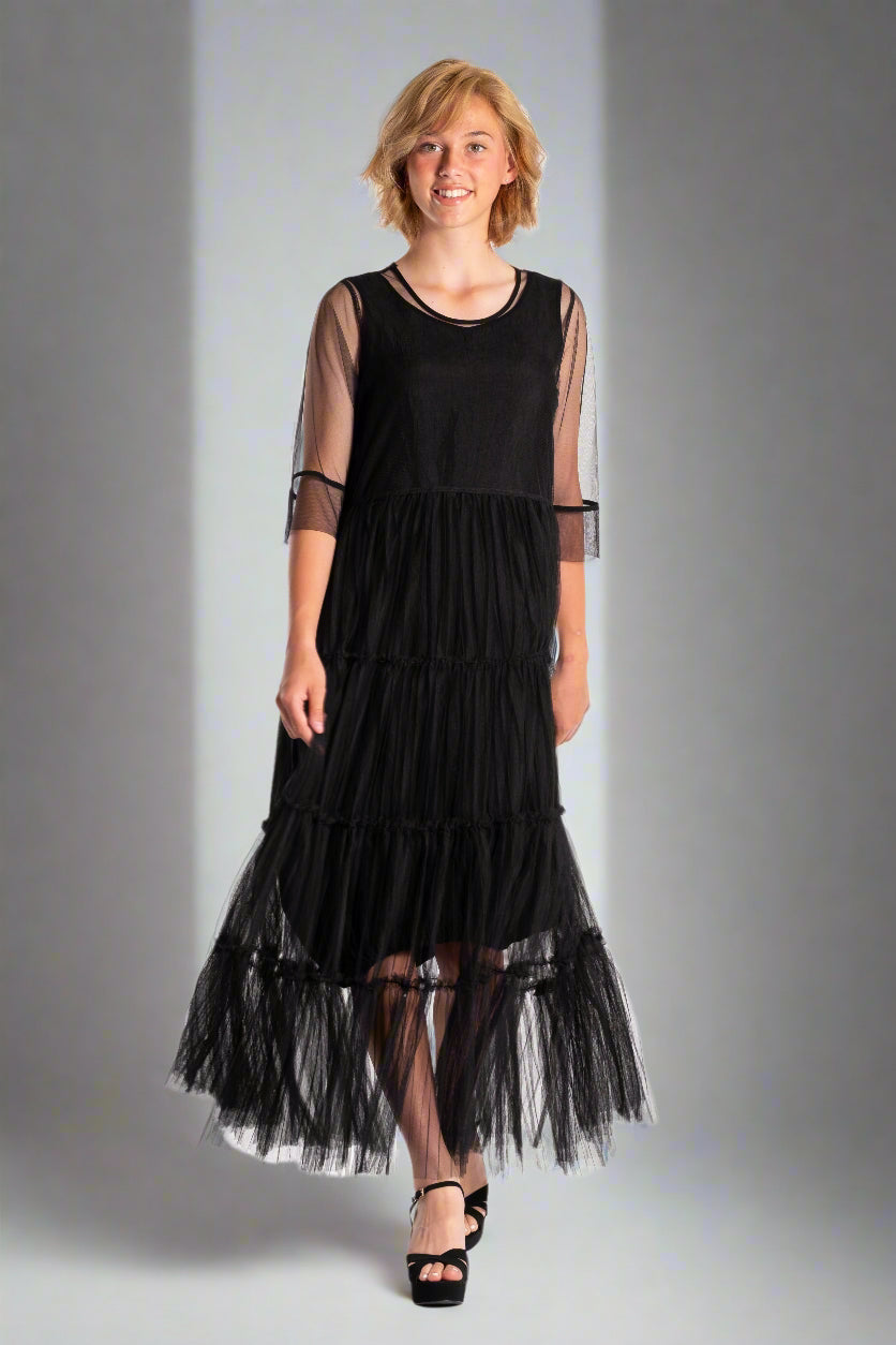 Woman wearing a black dress with sheer sleeves on a white background