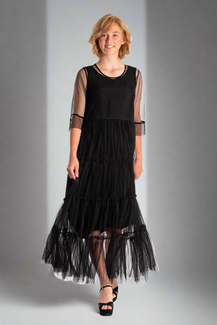 Woman wearing a black dress with sheer sleeves on a white background