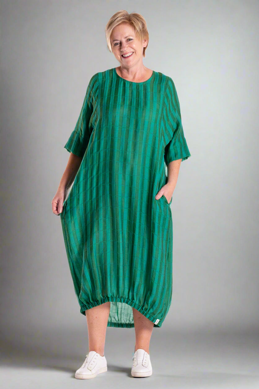 Woman wearing a green dress with white stripes on a white background