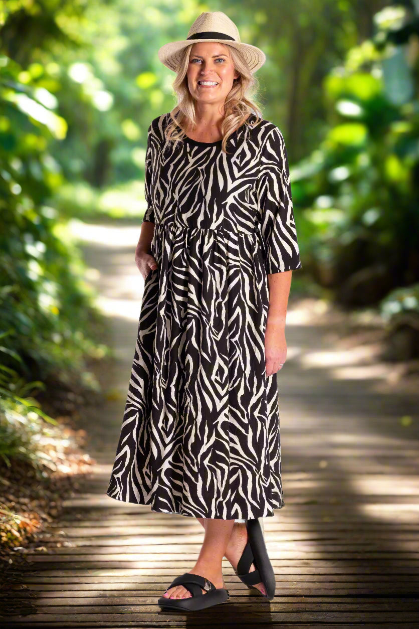 Woman wearing a black and white patterned dress with a hat on a white background