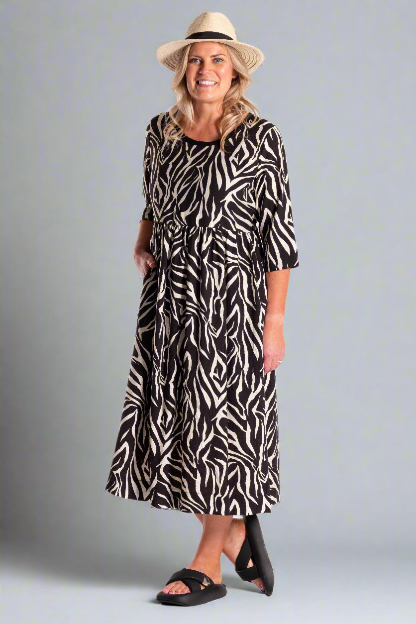 Woman wearing a black and white patterned dress with a hat on a white background
