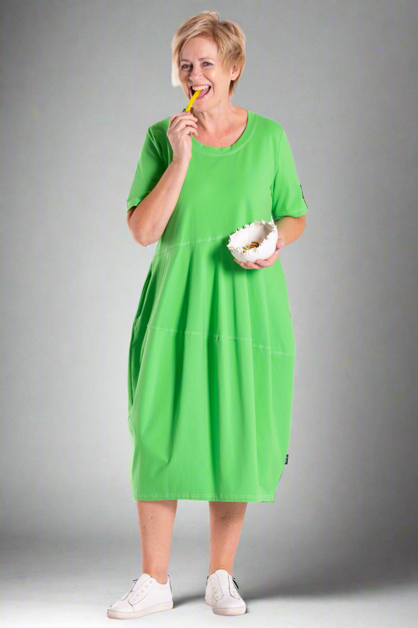 Person wearing a green dress holding a yellow object and a white bowl on a white background