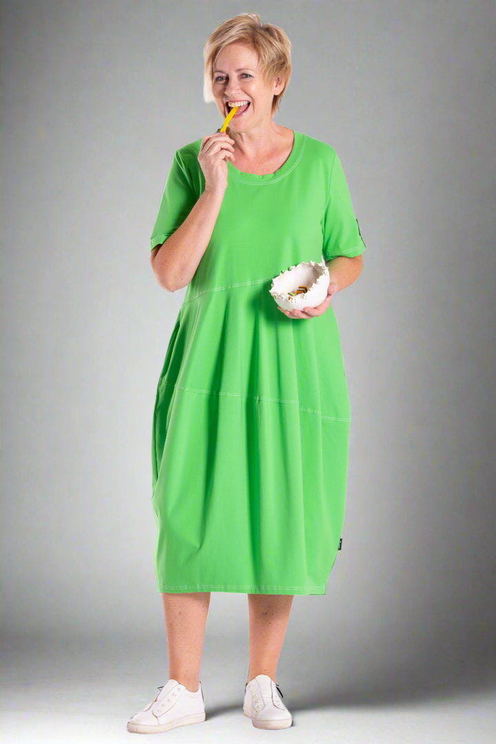 Person wearing a green dress holding a yellow object and a white bowl on a white background