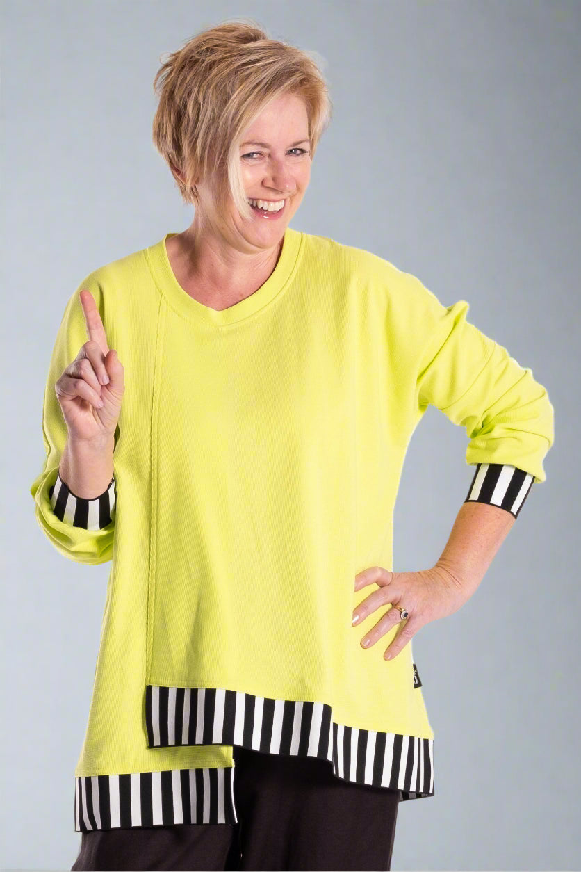 Person wearing a bright yellow top with black and white striped accents on a white background