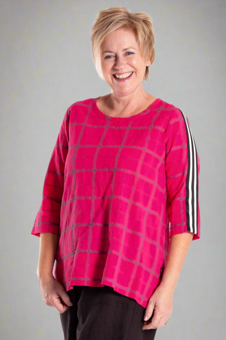 Woman wearing a pink checkered top and black pants on a white background