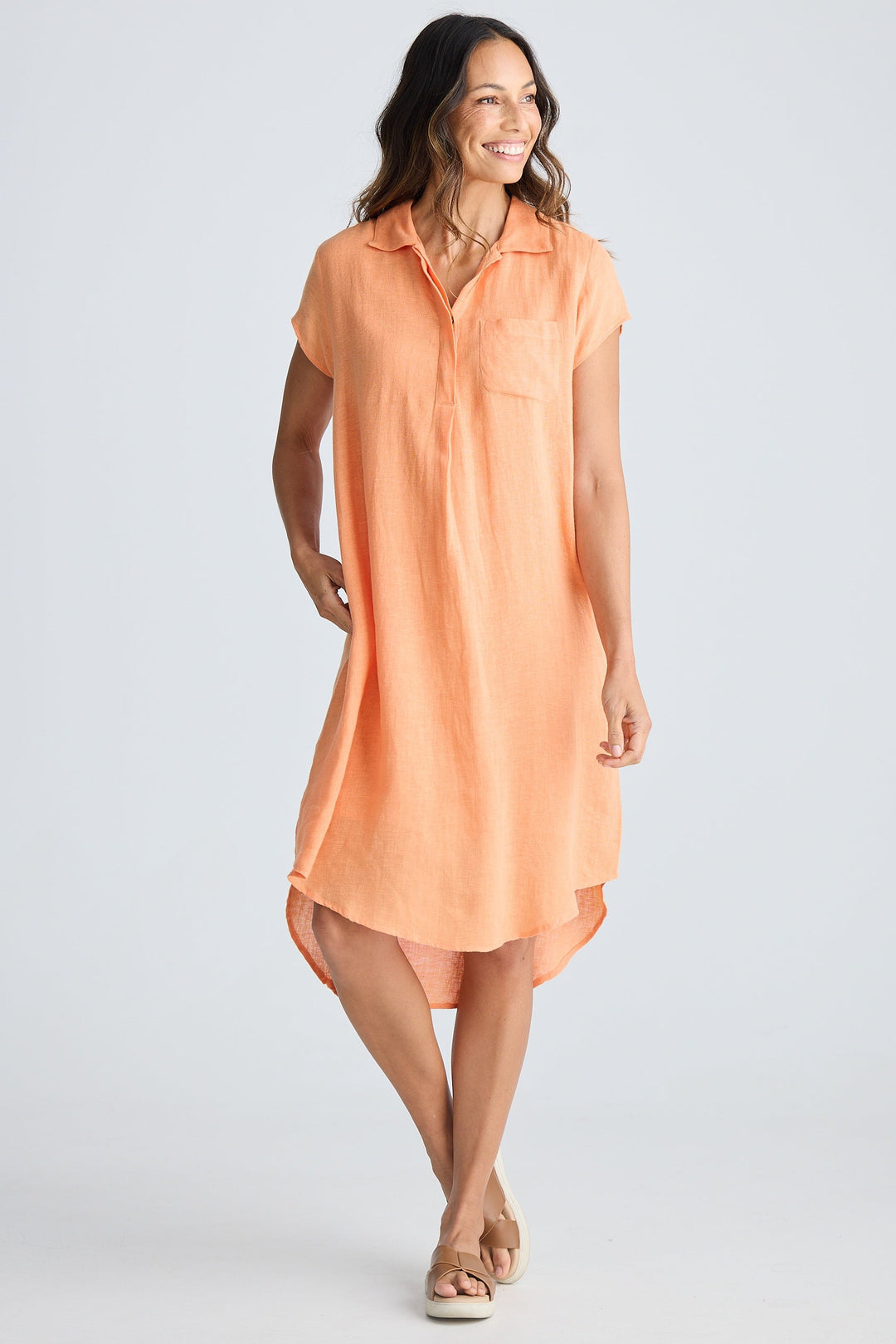Woman wearing a peach sleeveless dress on a white background