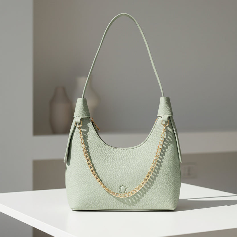Light green handbag with a gold chain detail on a white background