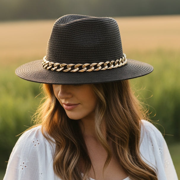 Black straw hat with a gold chain band on a white background