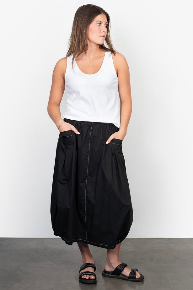 Woman wearing a white tank top and black wide-leg pants against a white background
