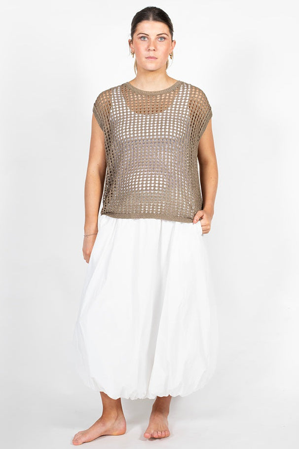 Woman wearing a brown mesh top and white pants on a white background