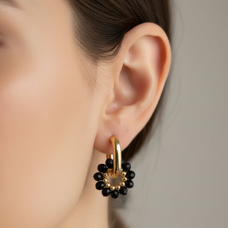 Pair of gold and black earrings on a light gray background