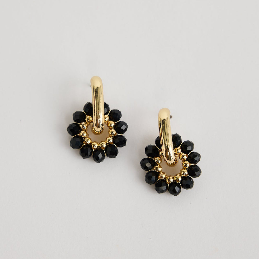 Pair of gold and black earrings on a light gray background