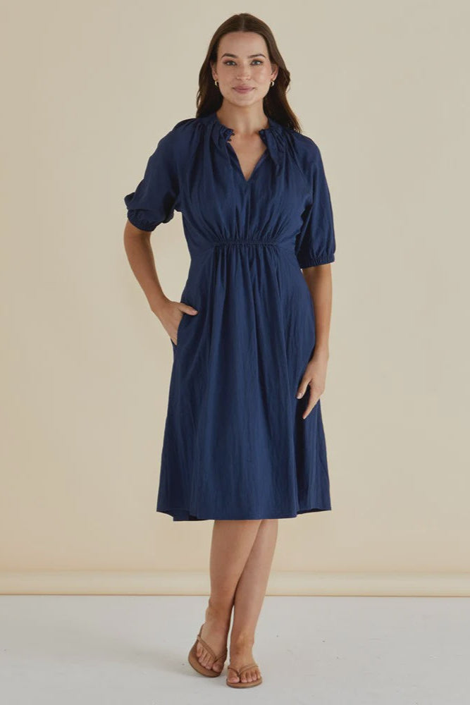 Woman wearing a blue dress against a beige background