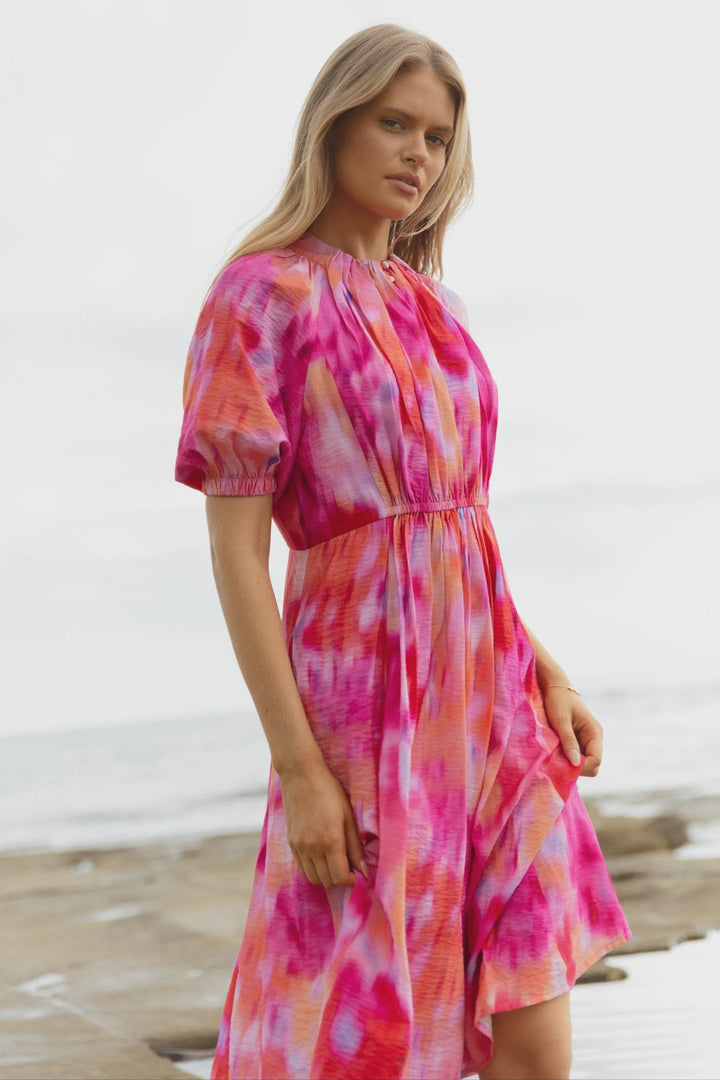 Woman wearing a pink and pink floral betty basics dress on a beach.