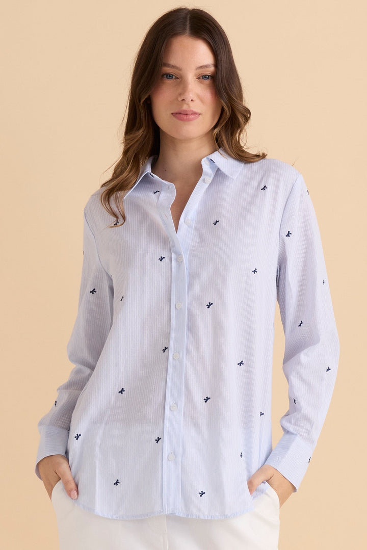 Woman wearing a light blue striped Betty Basics reid shirt with small blue bows over the sripes