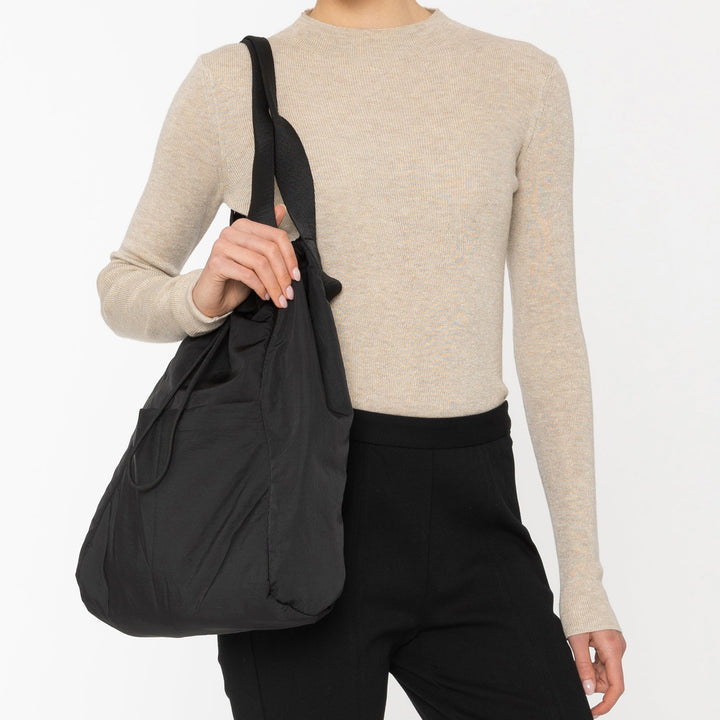 Woman holding a black tote bag against a white background
