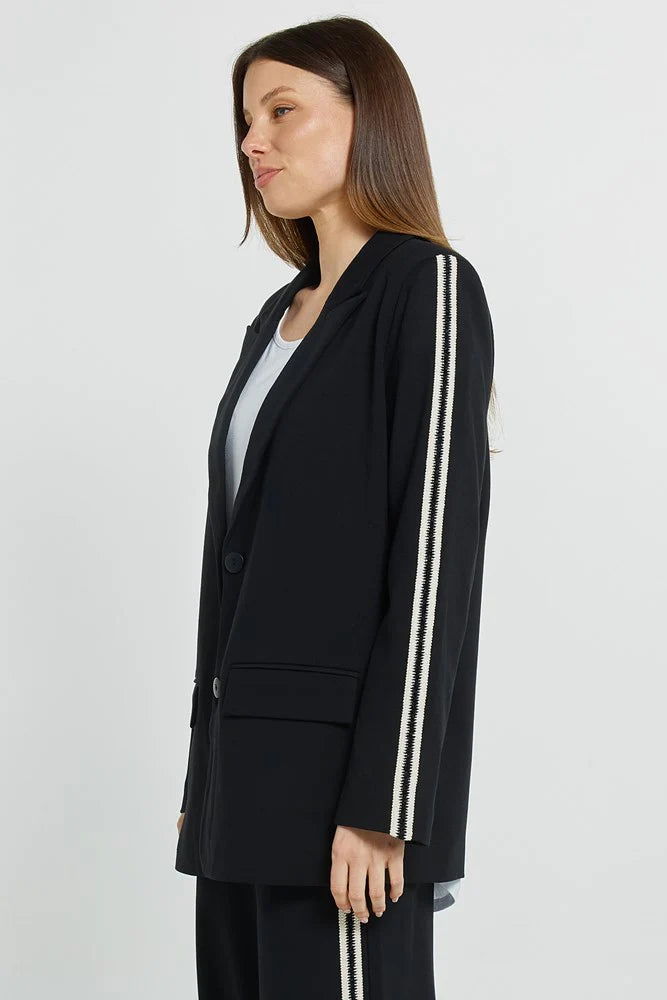 MODEL WEARING A BLACK STRTCH BLAZER WITH WHITE PINSTRIPE DETAIL ON HER ARM