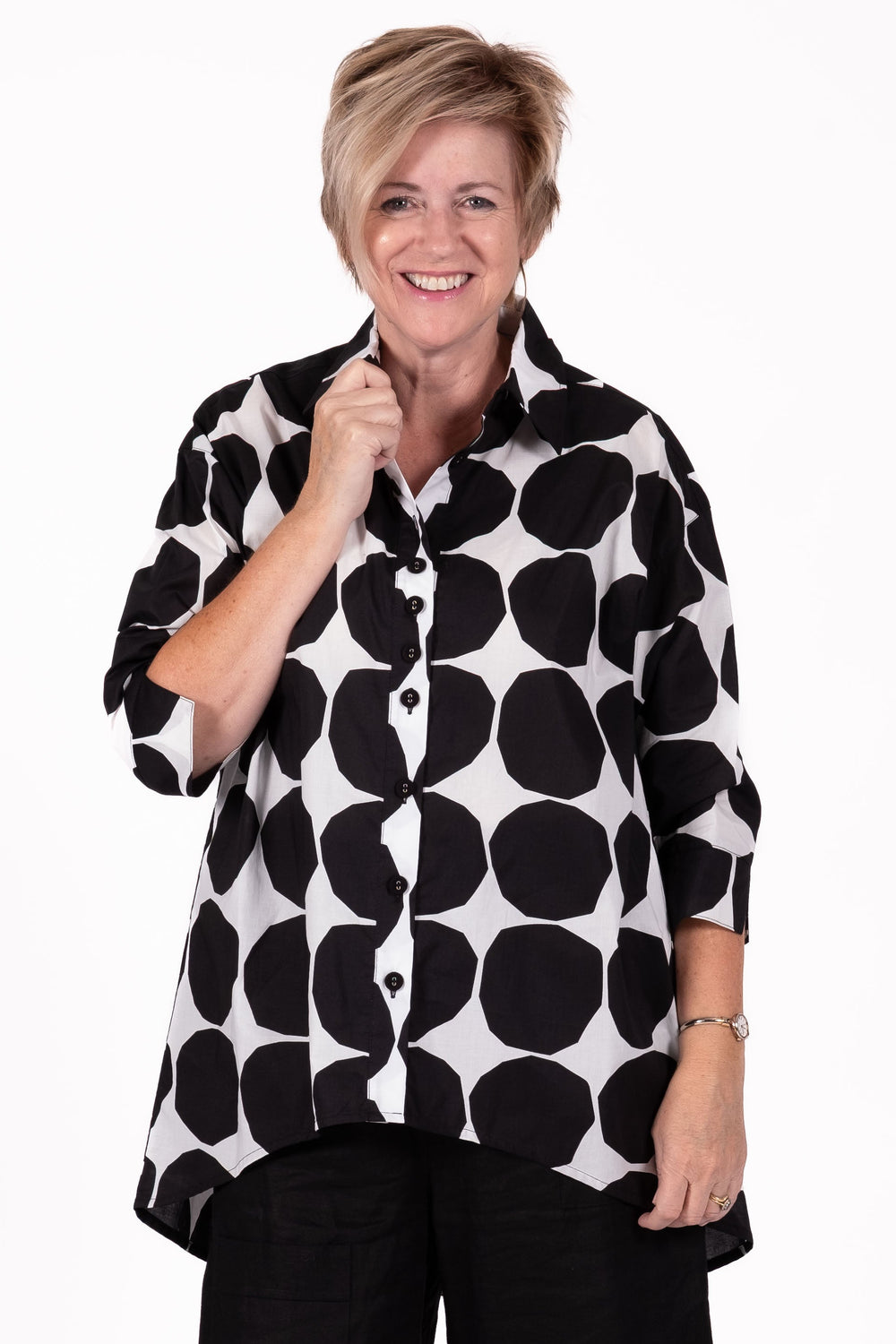 Woman wearing a black and white patterned shirt with black pants on a white background