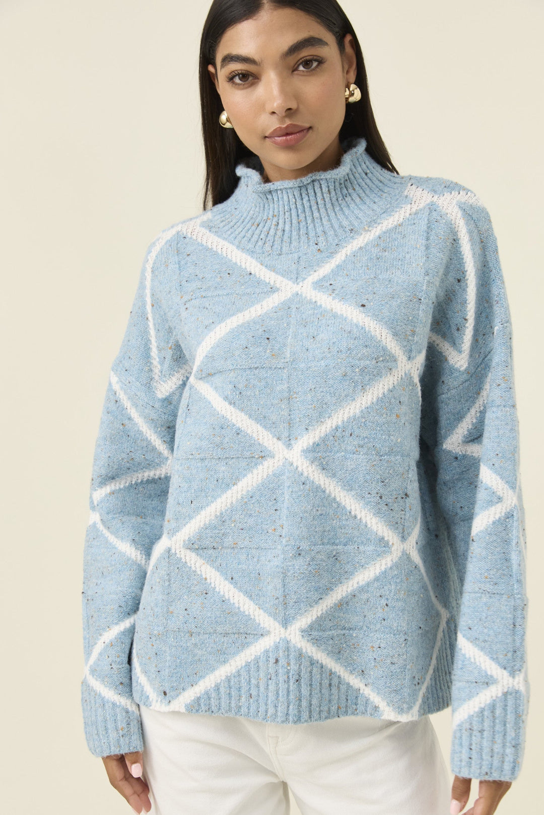 Woman wearing a blue and white patterned sweater against a beige background