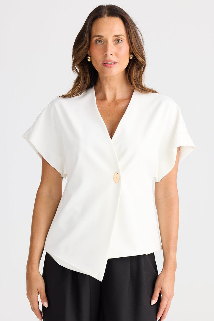 Woman wearing a white blouse with a V-neck and black shorts on a white background