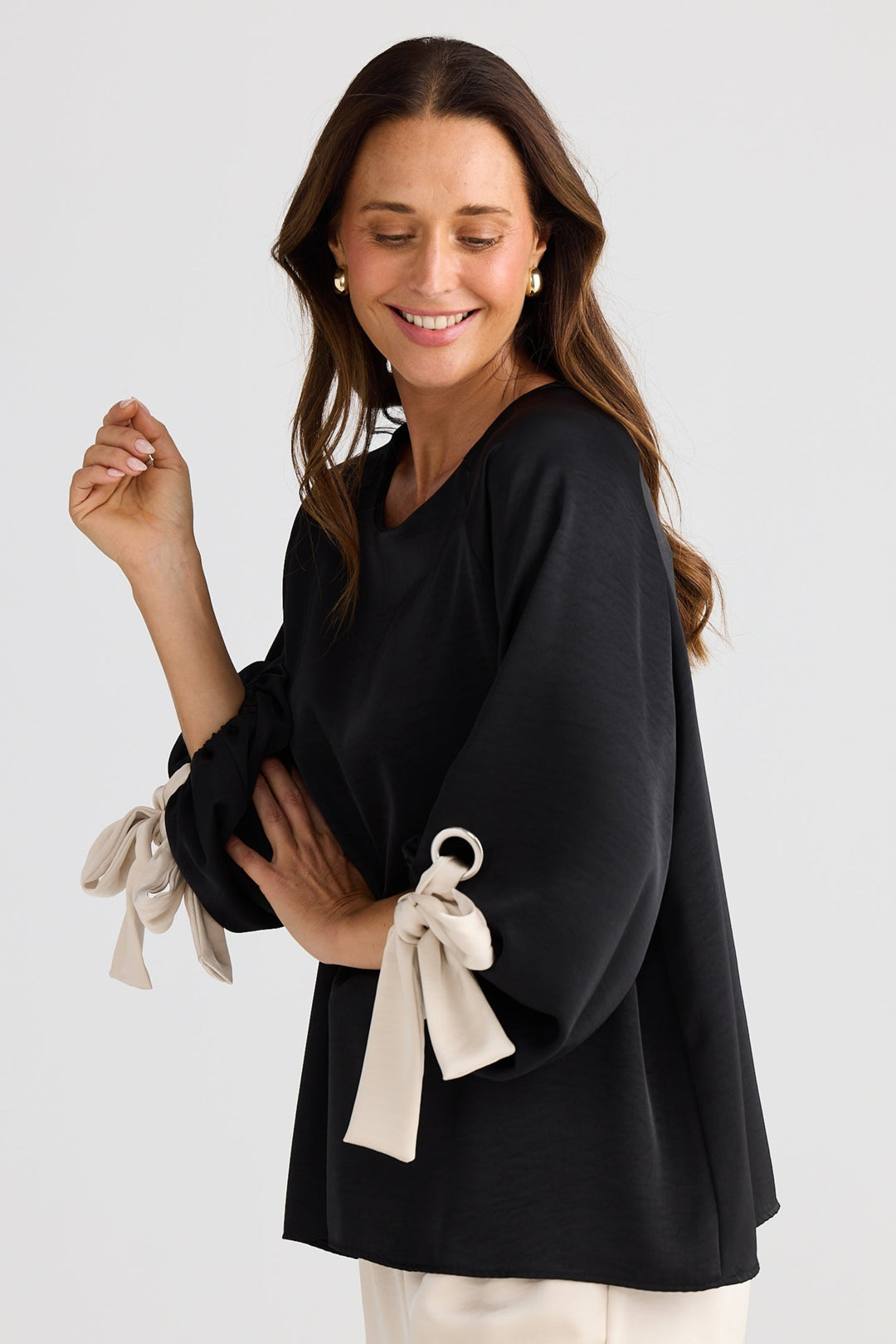 Woman wearing a black top with tie sleeves against a white background