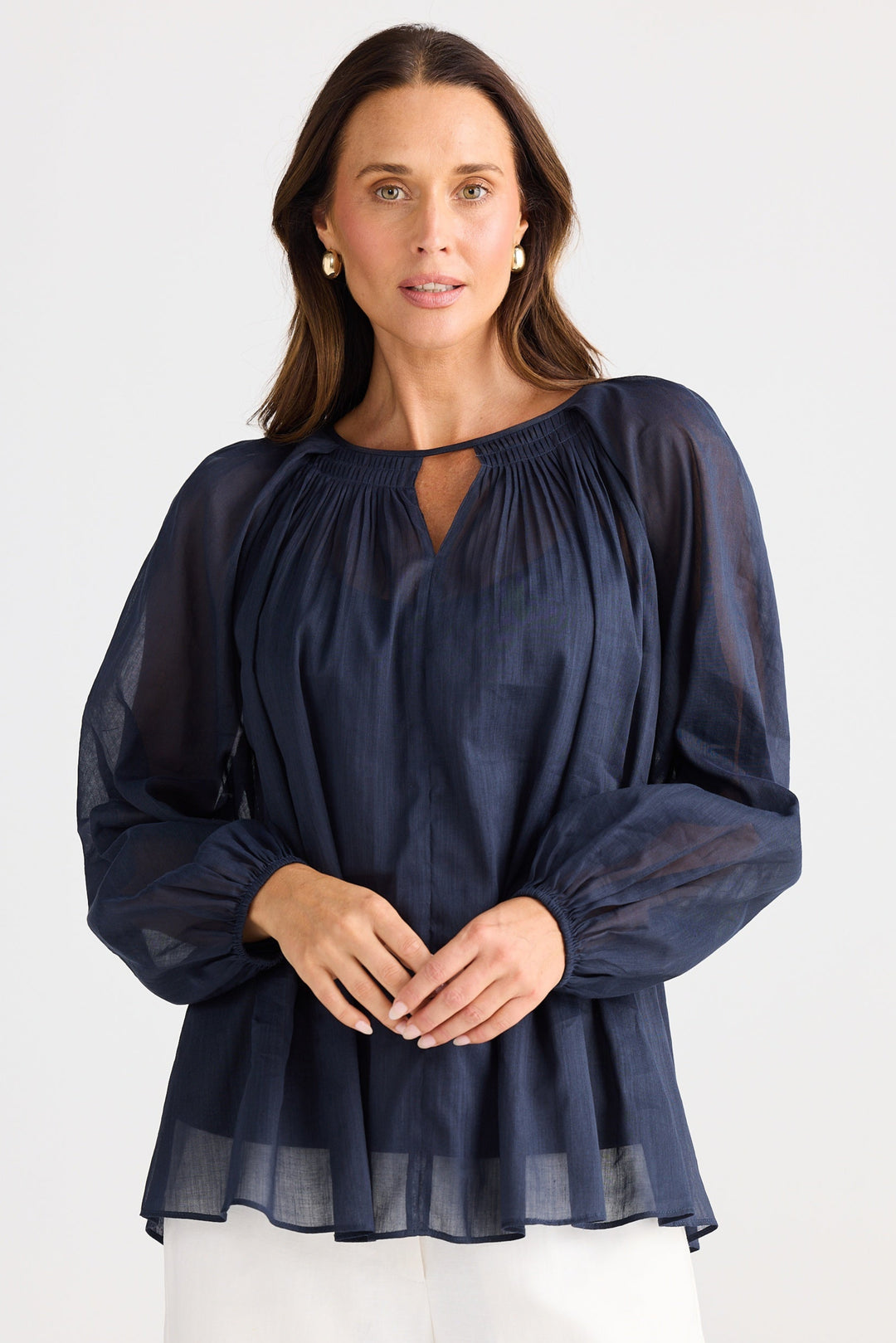 Woman wearing a navy blue blouse with long sleeves on a white background