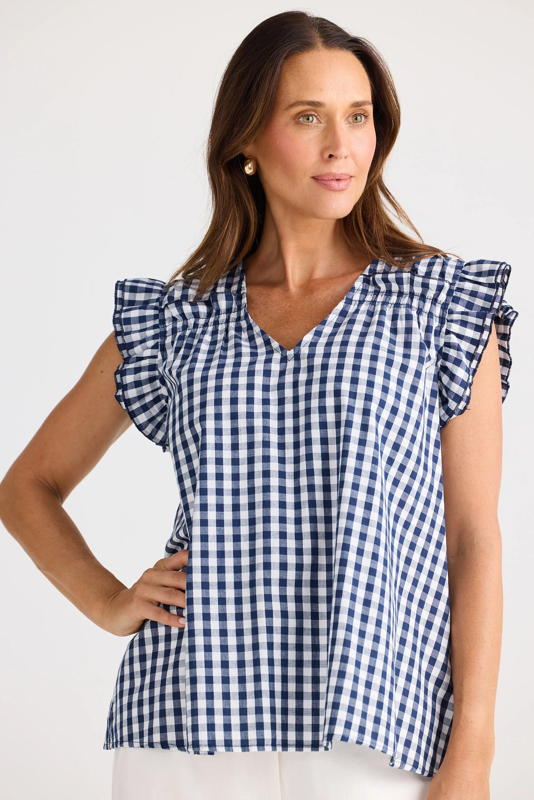 Woman wearing a blue and white checkered brave & true gingham top with ruffled sleeves on a white background