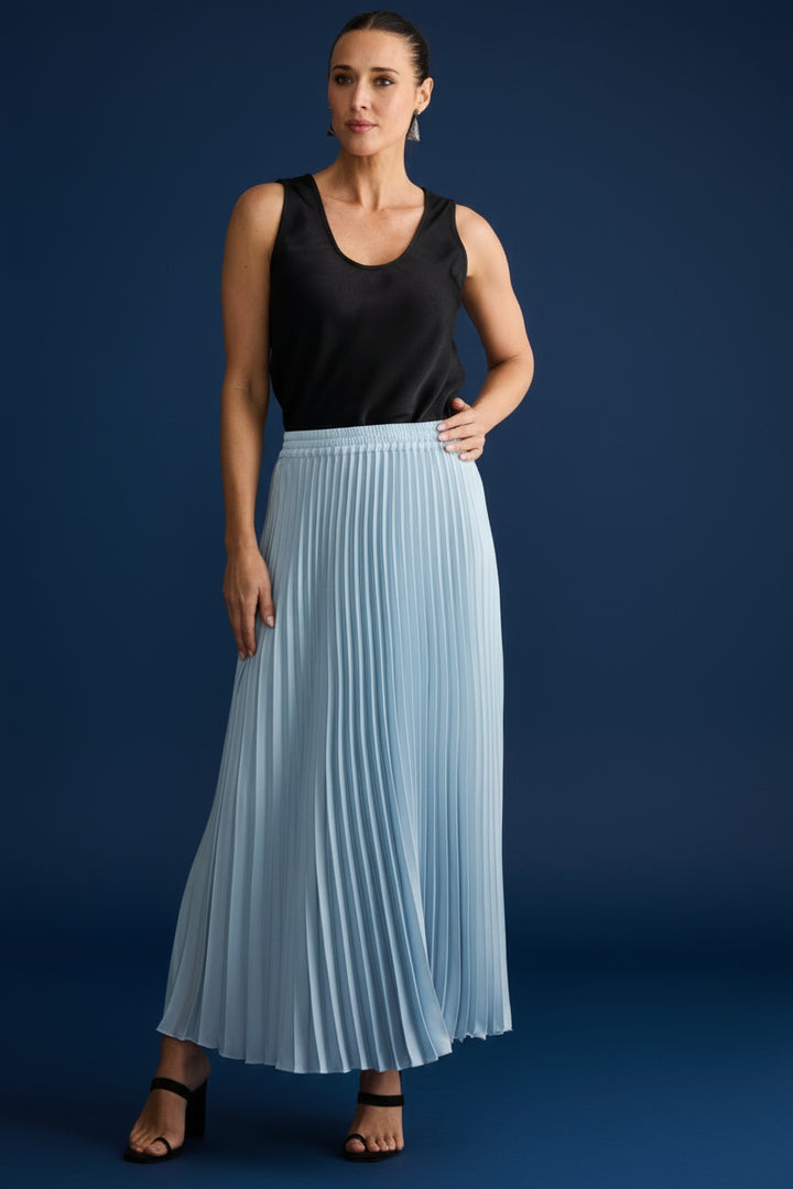 Woman wearing a black sleeveless top and light blue pleated skirt on a white background