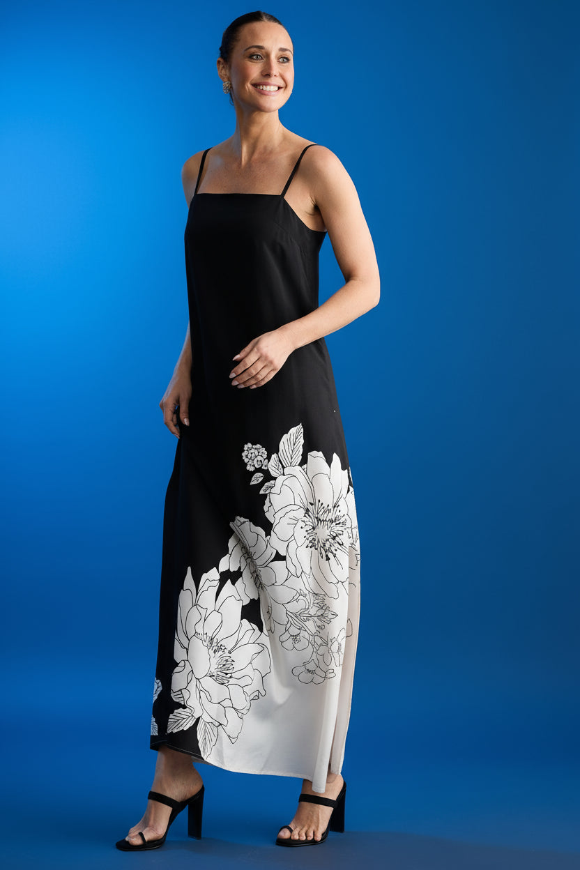 Woman wearing a black brave and true angelique slip dress with white floral patterns on a dark blue background