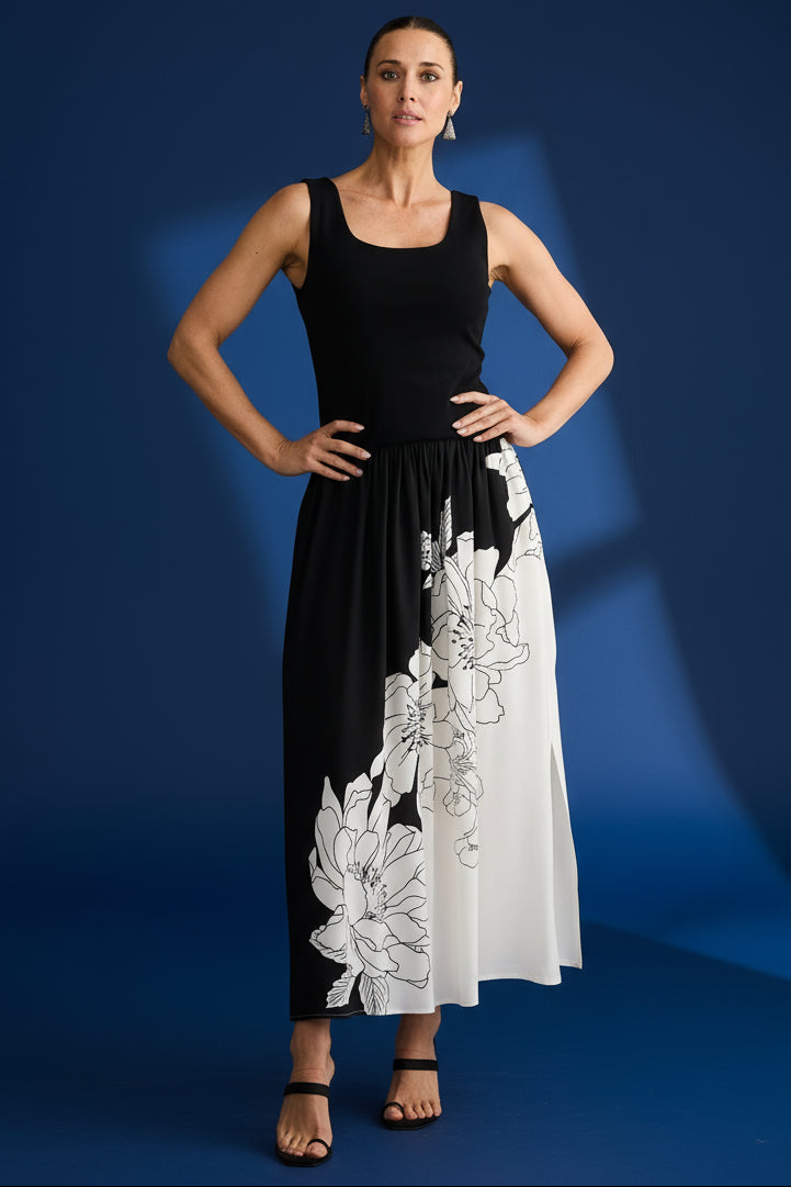 Woman wearing a black sleeveless brave & true maya dress with white floral patterns on a plain background