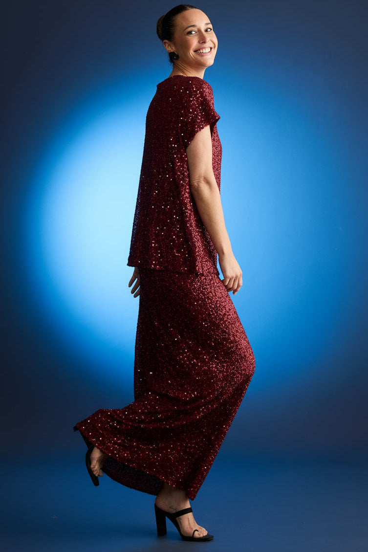 Woman wearing a red sequin brave & true sequin skirt against a dark blue background