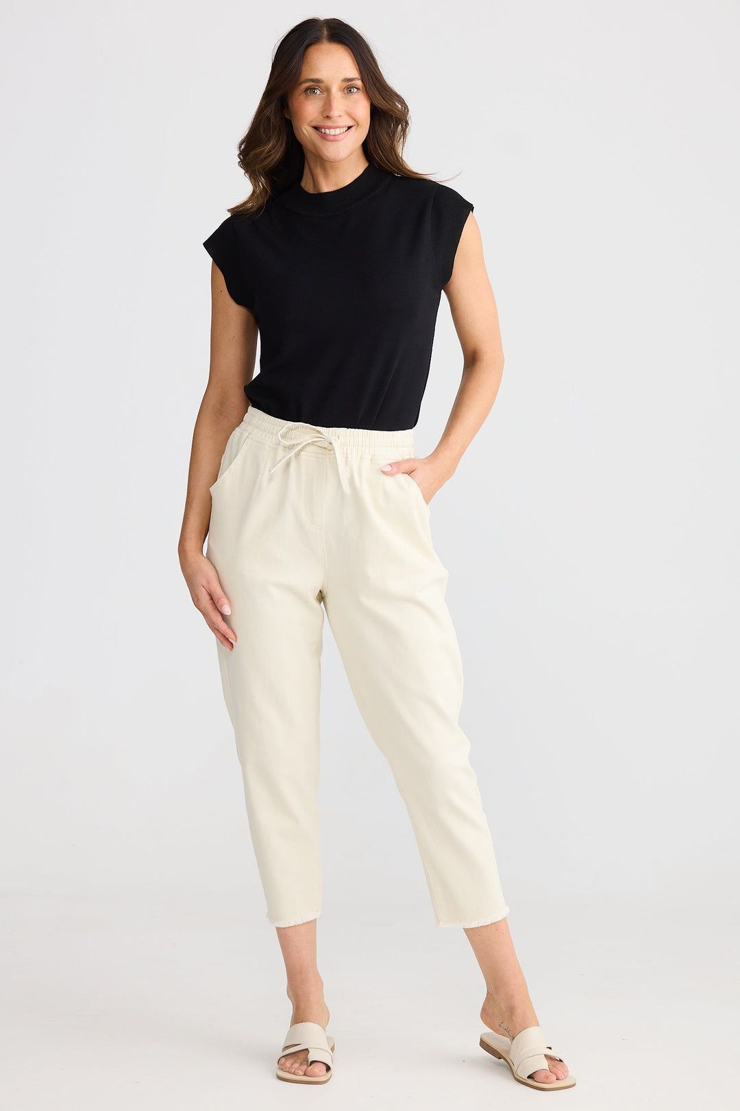 Woman wearing a black sleeveless top and bone brave & true wayfarer strtech pants on a white background
