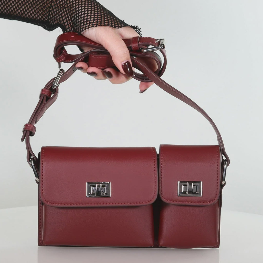 Red handbag held by a hand against a white background